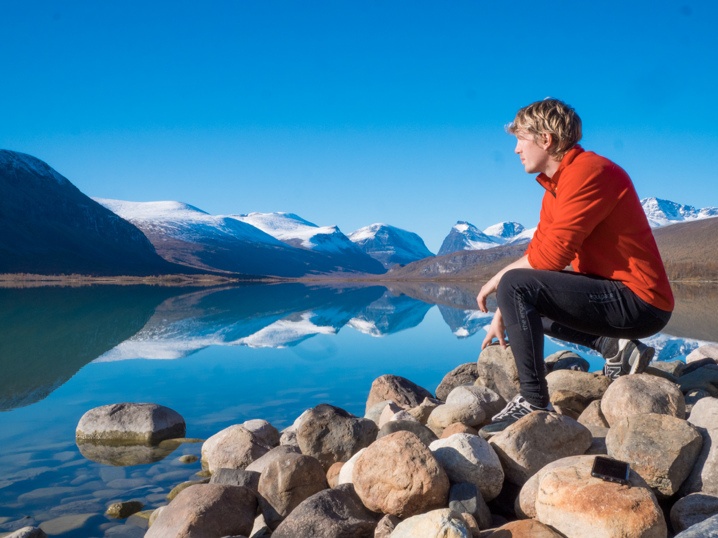 Martin Gårdling standing beside a glacial mountain lake during his country highpointing expedition