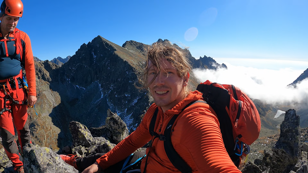 Martin Gårdling on a snowy summit ridge, arms raised after reaching a country high point